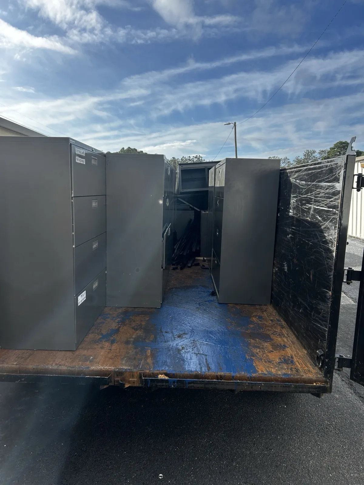 Office filing cabinets and furniture loaded onto a 813 Junk Solutions dump trailer