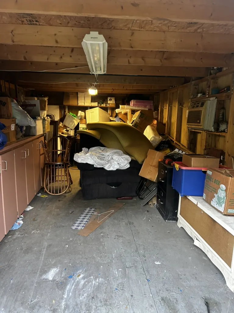 Garage packed with furniture, boxes, and clutter before a 813 Junk Solutions cleanout