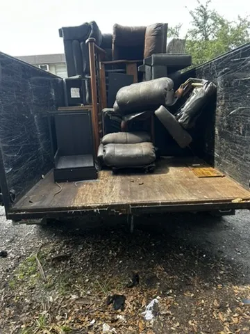 Household furniture and recliners loaded onto a 813 Junk Solutions trailer for haul-away